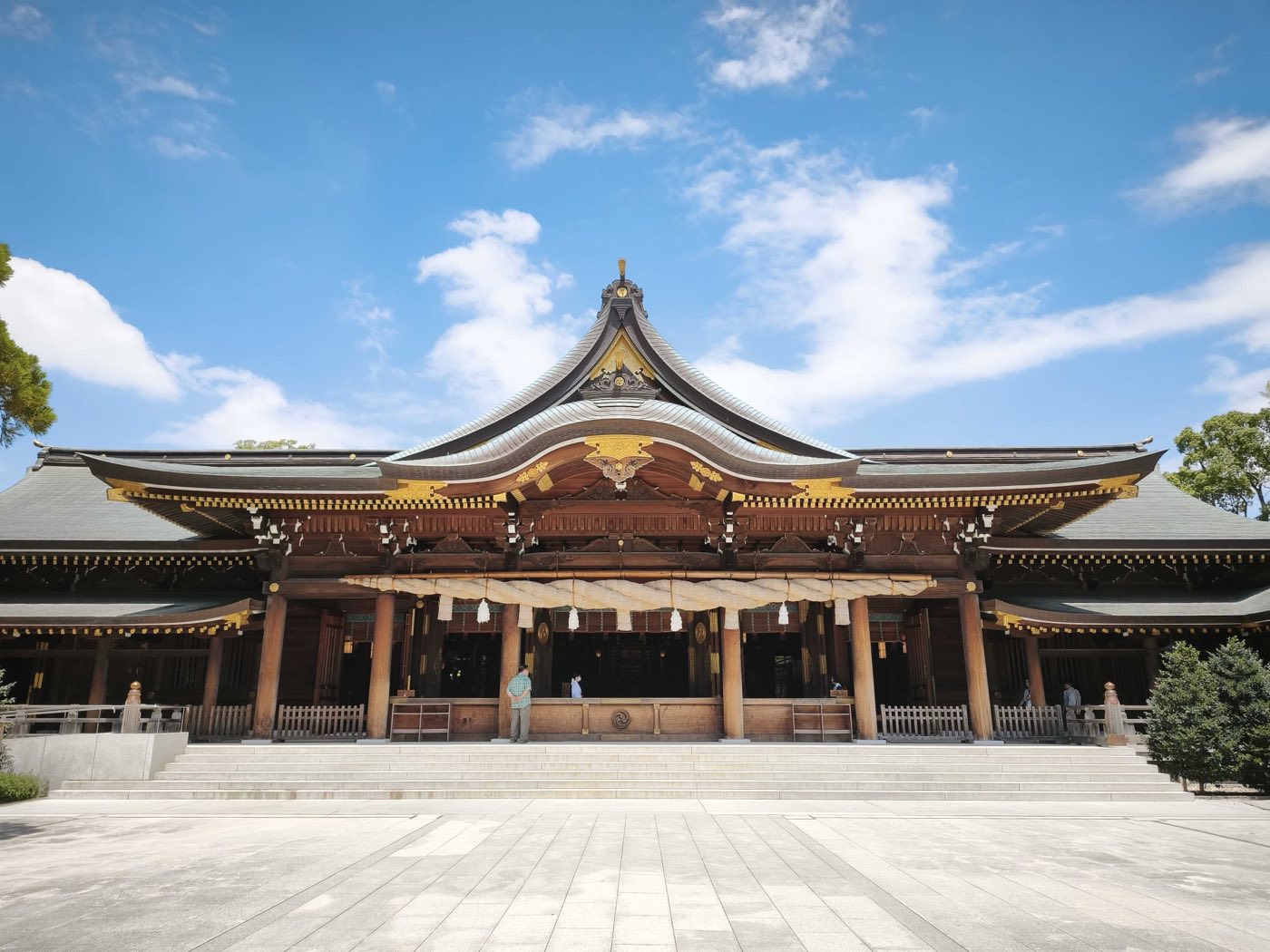 よく晴れた空の下、広い石畳の向こうに立つ寒川神社の社殿